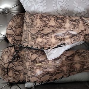 Thigh high snake skin boots with zipper and lace up the back.